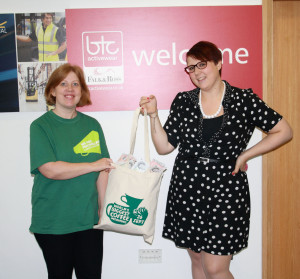 Eloise Davidson from Macmillan receives a bag of money from Katie Wright of BTC activewear